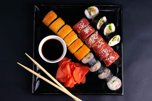 Top view of wooden platter with great set of delicious Nigiri sushi and Tempura rolls with Maki and Uramaki rolls on an rad background. Top views