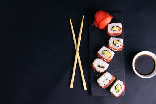 Top view of wooden platter with great set of delicious Nigiri sushi and Tempura rolls with Maki and Uramaki rolls on an rad background. Top views
