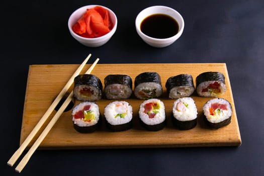 Sticks to reach for the roll, roll in the piece of packaging, next to the role of pickled ginger, everything stands on a red background. Top views