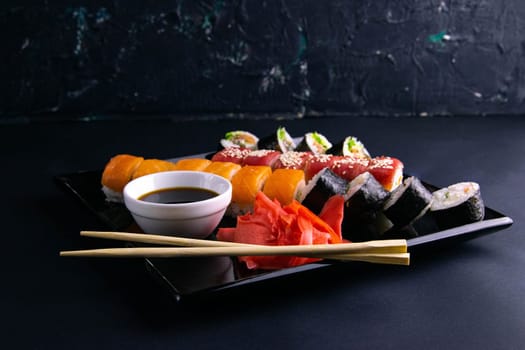 Top view of wooden platter with great set of delicious Nigiri sushi and Tempura rolls with Maki and Uramaki rolls on an rad background. Top views
