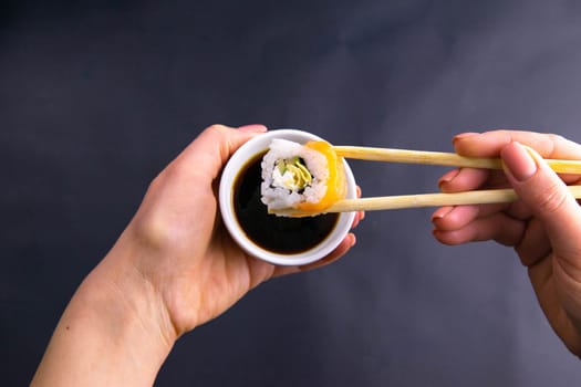 Sticks to reach for the roll, roll in the piece of packaging, next to the role of pickled ginger, everything stands on a red background. Top views