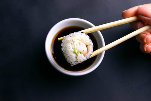 Sticks to reach for the roll, roll in the piece of packaging, next to the role of pickled ginger, everything stands on a red background. Top views
