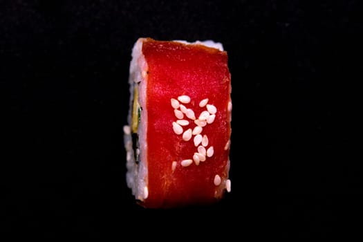 Sticks to reach for the roll, roll in the piece of packaging, next to the role of pickled ginger, everything stands on a red background. Top views