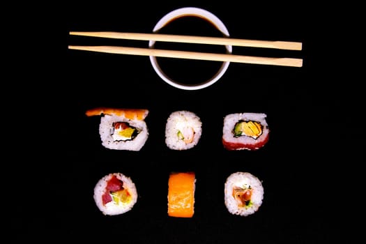A set of rolls of different kinds with sushi sticks isolated on a black background. Top views