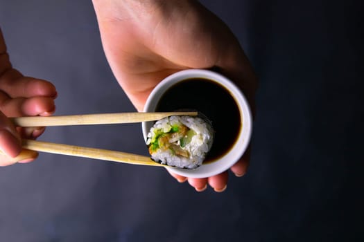 Sticks to reach for the roll, roll in the piece of packaging, next to the role of pickled ginger, everything stands on a red background. Top views