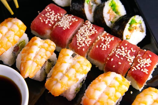 Top view of wooden platter with great set of delicious Nigiri sushi and Tempura rolls with Maki and Uramaki rolls on an rad background. Top views