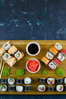 A set of rolls of different kinds with sushi sticks isolated on a black background. Top views