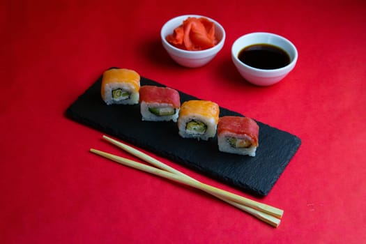 A set of rolls of different kinds with sushi sticks isolated on a black background. Top views