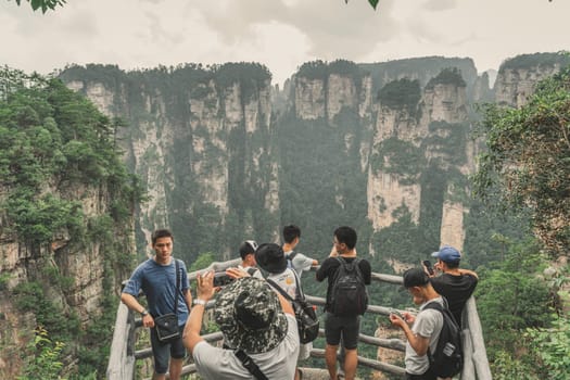 Zhangjiajie, China - August 2019 : Tourists taking pictures on mobile phones on the viewpoint in Tianzi mountain range, Avatar mountains nature park
