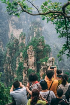 Zhangjiajie, China - August 2019 : Tourists taking pictures on mobile phones on the viewpoint in Tianzi mountain range, Avatar mountains nature park