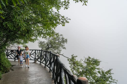 Zhangjiajie, China - August 2019 : Tourists walking on the popular narrow path on the top of the cliff which is called Sky Walk at Tianmen Mountain, Zhangjiajie forest National Park, Hunan Province