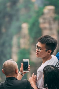 Zhangjiajie, China - August 2019 : Tourists taking pictures on mobile phones on the viewpoint in Tianzi mountain range, Avatar mountains nature park