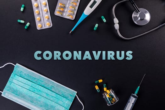 Protective mask, medicines, thermometer, stethoscope and syringe with coronavirus text on a black background. Novel coronavirus 2019-nCoV, MERS-Cov middle East respiratory syndrome coronavirus.