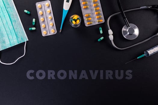 Protective mask, medicines, thermometer, stethoscope and syringe with coronavirus text on a black background. Novel coronavirus 2019-nCoV, MERS-Cov middle East respiratory syndrome coronavirus.