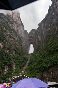 Zhangjiajie, China -  August 2019 : Massive tourist crowds waiting in torrential monsoon rain for public transport mini buses at the foot of Tianmen Mountain, the Zhangjiajie National Park, Hunan Province