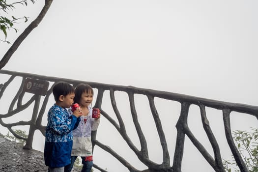 Zhangjiajie, China - August 2019 : Children eating ice cream on the popular narrow path on the top of the cliff which is called Sky Walk at Tianmen Mountain, Zhangjiajie forest National Park, Hunan Province