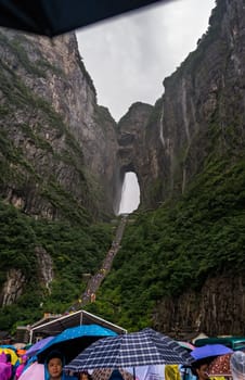 Zhangjiajie, China -  August 2019 : Massive tourist crowds waiting in torrential monsoon rain for public transport mini buses at the foot of Tianmen Mountain, the Zhangjiajie National Park, Hunan Province