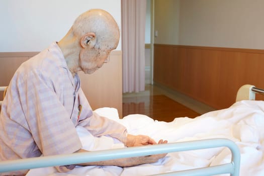 Jaoanese elderly man patient sitting on bed in hospital