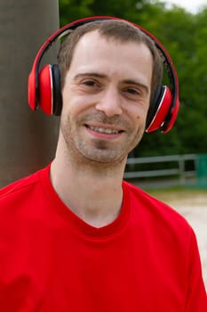 Young joyful Sportsman with red headphones in nature