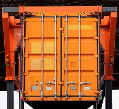 Lifting up orange cargo container in warehouse