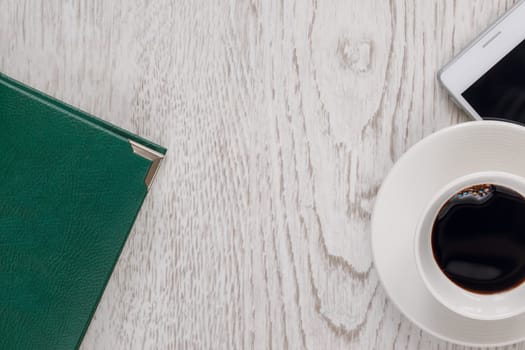 Business still life with a cup of coffee, a telephone on a wooden light surface