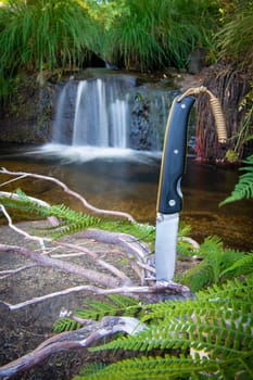 knife for bushcraft and survival in the wild near to a waterfall
