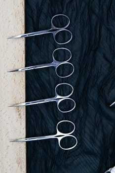 A set of cosmetic tools for manicure and pedicure stand on a black background. scissors and tongs. Top views