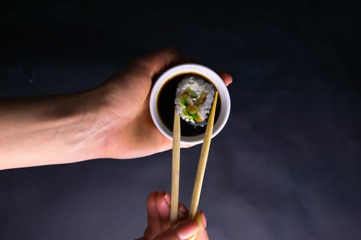 Rolls on a granite stand for sushi are laid out in the form of a dragon, next to stand sticks for sushi and soy sauce. Front views