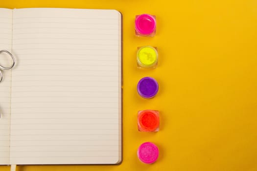 Set of cosmetic tools for manicure and pedicure on an orange background. Nearby there is an open notebook for writing, gel varnishes, a mill, nail files, scissors and nippers. Top views with clear space