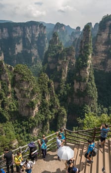 Zhangjiajie, China - August 2019 : Tourists taking pictures on mobile phones on the  Enchanting terrace viewpoint, Avatar mountains nature park