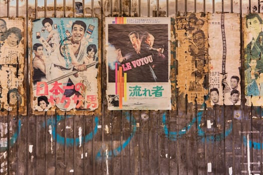 Old vintage retro japanese movie posters on underpass Yurakucho Concourse wall under the railway line of the station Yurakucho. Japanese noodle stalls and sake bars revive the nostalgic years of Showa air with old samurai posters, french nouvelle vague movie poster and placards glued to the walls of the tunnel.
