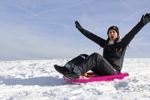 A young woman has fun sledging in winter
