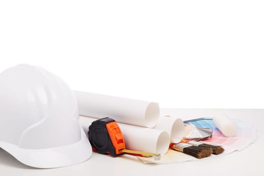 Architectural blueprints, construction hard hat, color palette guide, painting accessories on white background.  Architect workplace. Engineering tools. Concept of construction or design office