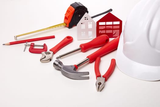 Construction hard hat, various tools and model of house on white background. Concept of construction