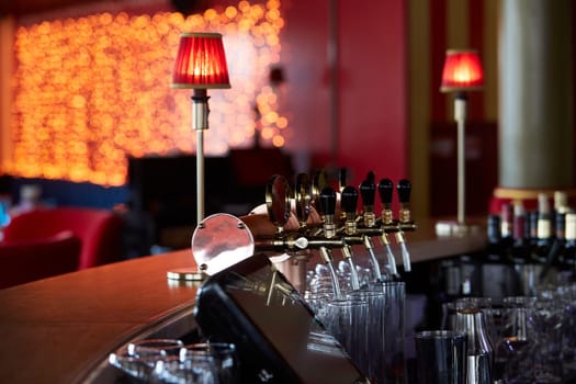 Bar counter with beer taps, glasses and bottles. Interior of pub, nightclub, cafe or restaurant