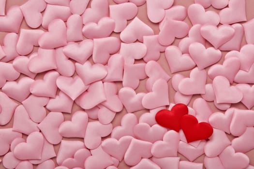 Two red hearts on valentine background from pink silk hearts. Valentine's Day. Top view with copy space. Design element for romantic greeting card, invitation. Hearts background. Wedding day