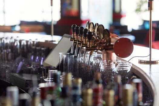 Bar counter with beer taps, glasses and bottles. Interior of pub, nightclub, cafe or restaurant