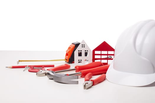 Construction hard hat, various tools and model of house on white background. Concept of construction