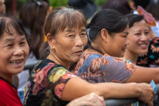 Zhangjiajie, China - August 2019 : Older chinese women queuing by the metal barrier at the Wullingyuan entrance to the Zhangjiajie national park, Hunan Province