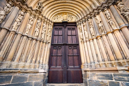 Grand doors of cathedral in Germany. Entrance in high arch with a lot of sculpture in it and statues on walls. Architecture of Europe.