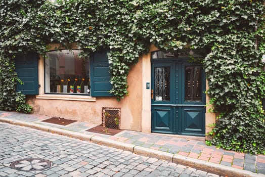 Beautiful street shop in Germany, Europe. Lush green on facade of building, cobblestone walkway in foregournd. Old architecture.