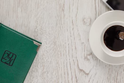 Business still life with a cup of coffee, a telephone on a wooden light surface