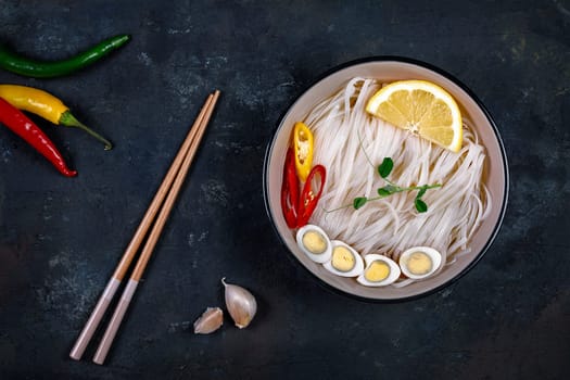 Rice noodles Asian cuisine with quail eggs, chili pepper and lemon, and green pea sprout