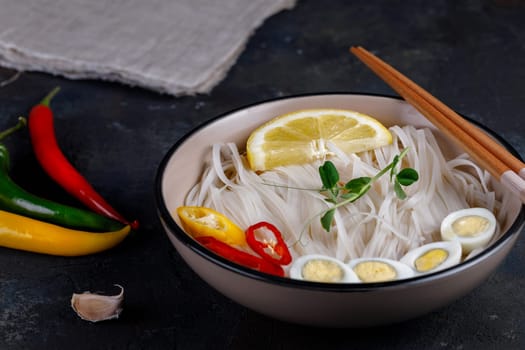 Rice noodles Asian cuisine with quail eggs, chili pepper and lemon, and green pea sprout
