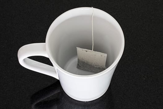 white mug black background tea bag closeup object single