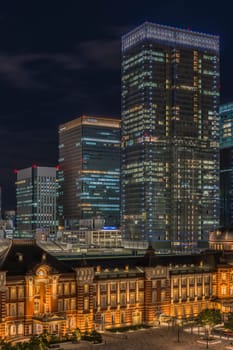 Marunouchi side of Tokyo railway station in the Chiyoda City, Tokyo, Japan.  The station is divided into Marunouchi and Yaesu sides in its directional signage. The station first called Central Station was built in 1914 directly in front of the Imperial Palace gardens. The three-story station building was designed by architect Tatsuno Kingo who also designed Manseibashi Station and the nearby Bank of Japan building. Much of the station was destroyed in B-29 firebombing on May 25, 1945. The bombing shattered the impressive rooftop domes. The station was quickly rebuilt within the year, but simple angular roofs were built in place of the domes, and the restored building was only two stories tall instead of three.