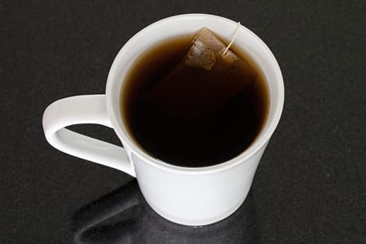 white mug black background tea bag liquid closeup object single