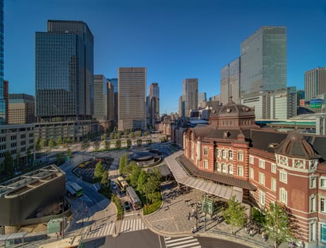 Marunouchi side of Tokyo railway station in the Chiyoda City, Tokyo, Japan.  The station is divided into Marunouchi and Yaesu sides in its directional signage. The station first called Central Station was built in 1914 directly in front of the Imperial Palace gardens. The three-story station building was designed by architect Tatsuno Kingo who also designed Manseibashi Station and the nearby Bank of Japan building. Much of the station was destroyed in B-29 firebombing on May 25, 1945. The bombing shattered the impressive rooftop domes. The station was quickly rebuilt within the year, but simple angular roofs were built in place of the domes, and the restored building was only two stories tall instead of three.
