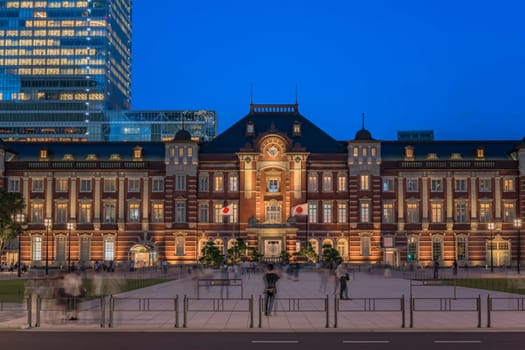 Night view on Marunouchi side of Tokyo railway station in the Chiyoda City, Tokyo, Japan.  The station is divided into Marunouchi and Yaesu sides in its directional signage. The station first called Central Station was built in 1914 directly in front of the Imperial Palace gardens. The three-story station building was designed by architect Tatsuno Kingo who also designed Manseibashi Station and the nearby Bank of Japan building. Much of the station was destroyed in B-29 firebombing on May 25, 1945. The bombing shattered the impressive rooftop domes. The station was quickly rebuilt within the year, but simple angular roofs were built in place of the domes, and the restored building was only two stories tall instead of three.