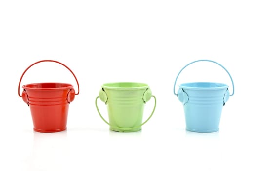 Three metal buckets of different colours with handle, isolated on white background